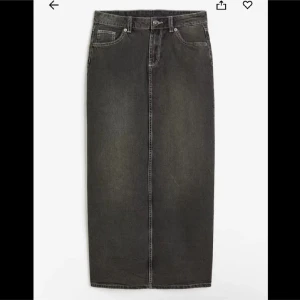 Svart jeanskjol - Snygg svart långkjol i jeansmaterial med klassisk femficksdesign. Kjolen har en rak passform och stängs med knapp och dragkedja framtill. Perfekt för en stilren look.