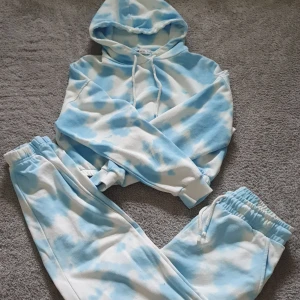 Blåvita mjukisbyxor+cropped hoodie i tie-dye - Säljer ett par mjukisbyxor från Femivica i blåvitt tie-dye-mönster. Samt en hoodie som är croppad i samma mönster. Byxorna har resår och dragsko i midjan samt resår vid bensluten. Hoodien har resår vid magen. Perfekta för en avslappnad stil och supermjuka i materialet. XS i byxorna o S i hoodien. Köpt på New Yorker. 