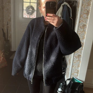 Mörkblå teddyjacka med dragkedja - Säljer en mörkblå teddyjacka med oversized passform och lång ärm. Jackan har en grov struktur och stängs med dragkedja framtill. Perfekt för kyligare dagar och ger en avslappnad look.