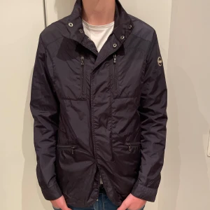 Colmar fieldjacka  - Mörkblå field jacka från Colmar. Det är storlek S med nummer 46 i ”Colmar storlek” för de som undrar. Jackan har flera knappar och dragkedjan som sätter ihop jackan i mitten börjar lite längre upp (syns på bild 3). Jackan är väldigt tunn och är i fint skick. Skicka gärna om du har frågor eller prisförslag!