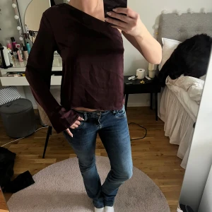Vinröd oneshoulder topp - Snygg vinröd oneshoulder topp med lång ärm. Perfekt för en unik och stilren look. Passar bra till både jeans och kjol.