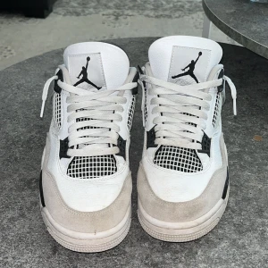 Nike Air Jordans i vitt och svart - Säljer ett par klassiska Nike Air Jordans i vitt och svart. Skorna har snörning och en ikonisk design med Jumpman-loggan. Perfekta för dig som älskar stil och komfort.