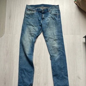 Blå jeans från Weekday - Snygga blå jeans från Weekday med en klassisk femficksdesign och knappgylf. Perfekta för en avslappnad stil. Märkeslappen i brunt läder ger en extra touch.