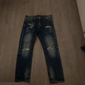 Mörkblå distressed jeans från Supply & Demand - Säljer ett par mörkblå jeans från Supply & Demand i storlek XS från JD SWEDEN Jeansen har slitna detaljer, dragkedja vid fickan och en cool, tvättad look. Perfekta för dig som gillar streetstyle och vill ha något unikt i garderoben.