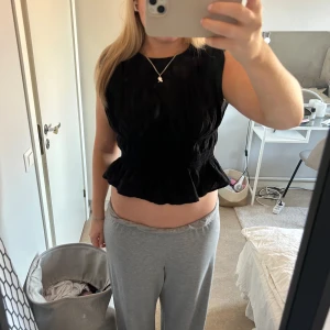 Svart volangblus - Säljer en svart blus med volangkant nertill. Blusen är ärmlös och har en lätt rynkad struktur som ger en fin form. Perfekt att styla med både jeans och kjol.🤩