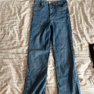 Blå jeans med slits - Säljer ett par blå jeans med hög midja och raka ben. Byxorna har en snygg slits nertill på benen. 