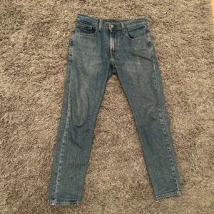 Levi's 502 Hi-Ball jeans blå - Säljer ett par klassiska blå Levi's 502 Hi-Ball jeans med normal passform och raka ben. Jeansen har fem fickor, dragkedja och knapp i midjan samt den ikoniska Levi's-lappen bak. Perfekta för dig som gillar tidlös denimstil.