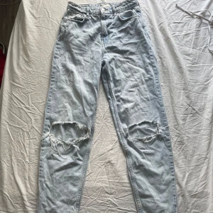 Ljusa jeans med slitningar från Gina tricot - Säljer ett par ljusa jeans från Gina tricot med coola slitningar på knäna. Perfekta för en avslappnad stil.