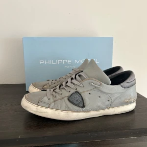 Grå Philippe Model - Snygga grå skor Philippe Model med en unik design. Skorna har snörning och en rund tå, med en kontrasterande svart detalj på sidan. Perfekta för en stilren look. Använda man har fortfarande mycket kvar att ge. Box mm följer med