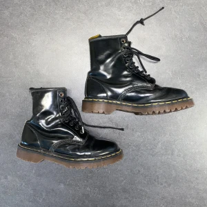 Klassiska Dr. Martens kängor - Klassiska svarta Dr. Martens boots i skinn med snörning och grov sula. Ikonisk gul söm runt sulan och högre skaft.  Något slitna i skinnet.  Strl: 37.   /   Spara skärmtid, besök våra butiker i Sthlm, Malmö & Gbg. New arrivals daily + studentrabatt i alla våra butiker! Hitta till din närmsta butik på humansecondhand.se.   HUMANA Second Hand erbjuder 14 dagars retur, även via plick. Returer skickas med PostNord. Vid retur kontakta support@plick.se.