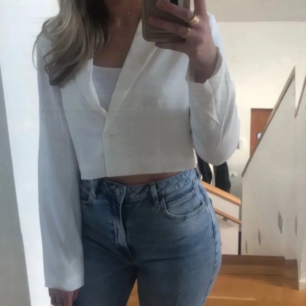 Säljer en stilren vit croppad kavaj från Nelly. Jackan har lång ärm, klassisk krage och knäppning framtill. Perfekt att styla med jeans eller kjol för en trendig look.. Puvut & Bleiserit.