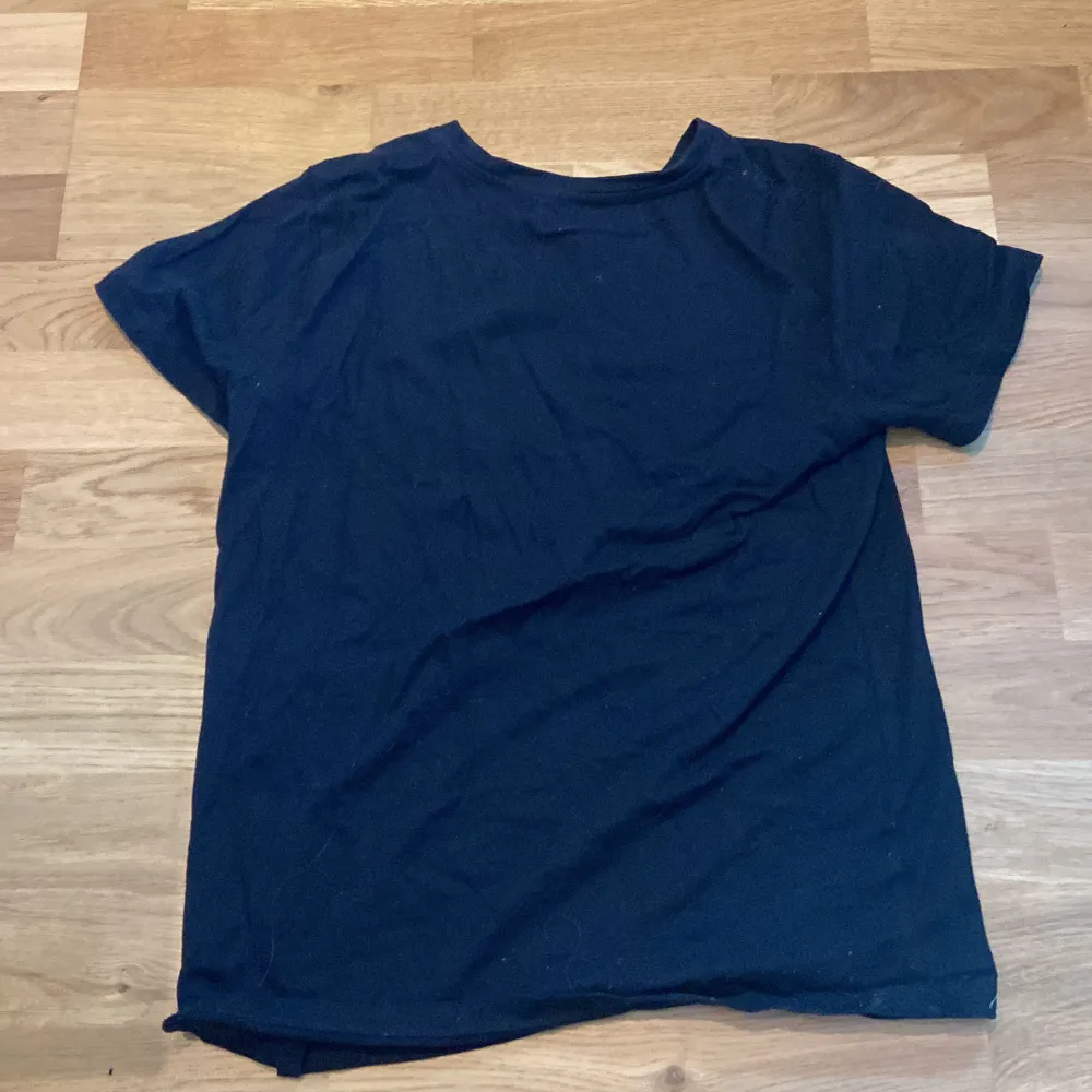 Säljer en svart t-shirt med ett coolt Among Us-tryck i flera färger. Texten 'There is an impostor among us' pryder framsidan tillsammans med karaktärer från spelet. Perfekt för fans av spelet!. T-paidat.