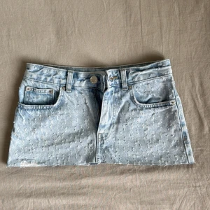 Ljusblå jeanskjol med slitningar från F3 Sister - Säljer en ljusblå jeanskjol från F3 Sister i storlek XS. Kjolen har en klassisk femficksdesign, rå kant nertill och diskreta slitningar över hela tyget för en trendig look. Perfekt för dig som gillar denim och vill ha en kortkjol med attityd.