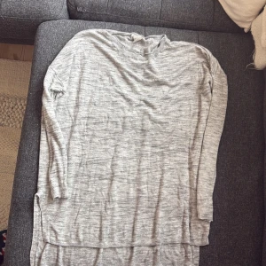 Grå långärmad tröja - Säljer en stilren grå långärmad tröja i mjukt material. Perfekt för en avslappnad look. Tröjan har en rund halsringning och ribbade kanter vid ärmslut och nederkant.