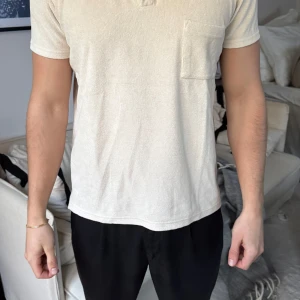 Beige frotté piké från Aveny - Säljer en stilren beige t-shirt i frotté med krage och korta ärmar. Perfekt för en avslappnad look. Har en praktisk bröstficka för extra stilpoäng.