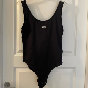 Levi’s Svart body, stl M - Snygg svart body från Levi's i klassisk modell med rundad halsringning och tryckt logga framtill. Tillverkad i stretchigt material som sitter skönt på kroppen. Perfekt för sommaren. Aldrig använt.