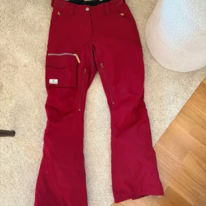 Wearcolour Vinröda Termobyxor / Skidbyxor / Snowboardbyxor / Täckbyxor - Super snygga täckbyxor från Wearcolour för skidor/snowboard. Justerbara i midjan, dragkedja vid innerlåren, över pjäxorna och fickor. Lite slitningar på dragkedjorna men annars super fint skick! Fodrade!