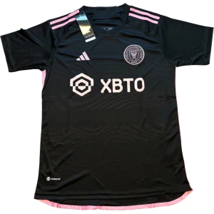 Inter Miami svart fotbollströja Adidas - Snygg svart Inter Miami fotbollströja från Adidas med rosa detaljer och klubbmärke på bröstet. Tröjan har korta ärmar, rosa ränder på axlarna och rosa logga samt sponsortryck framtill. Tillverkad i lätt och ventilerande polyester.