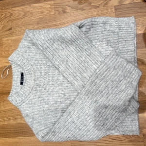 Ljusgrå stickad tröja från Gina Tricot - Supermysig ljusgrå stickad tröja från Gina Tricot. Tröjan har en klassisk rund halsringning, ribbade muddar och är långärmad. Perfekt för lager-på-lager och chill dagar. Snyggt enkel och passar till allt!