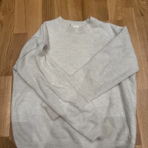 Ljusgrå stickad tröja Gina Tricot - Mysig ljusgrå stickad tröja från Gina Tricot i storlek 158/164. Tröjan har rund halsringning, långa ärmar och ribbade muddar vid ärmslut och nederkant. Perfekt för lager-på-lager under kyliga dagar.