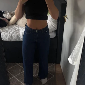 Mörkblå high waist wide jeans - Snygga mörkblå jeans med hög midja och raka, vida ben. Klassisk femficksmodell med knapp och dragkedja framtill. Perfekt massform och sitter bra och formar kroppen. 
