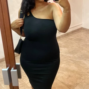 Svart enaxklad klänning med gulddetalj - Mycket bra skick, endast använd två gånger. Den har en guldig kedjedetalj på ena armen, det syns lite på andra bilden. Köparen står för frakten. storlek M men passar även L.