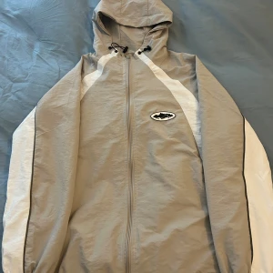 Grå Corteiz Vindjacka - Helt ny Corteiz vindjacka. Endast testad på ett par gånger. Är 183cm lång och den passar mig fint i längden. Har även spännband vid botten av jackan så den går att tajtas till. Tillkommer dock ingen original förpackning.