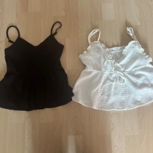 Svart och vit linnetopp från SHEIN - Två snygga linnetoppar från SHEIN i storlek 12-13 år. En svart ribbad topp med smala axelband och en vit topp med volangdetaljer och knyt framtill. Perfekta för sommaren och lätta att matcha till olika outfits. 2 för 50❤️