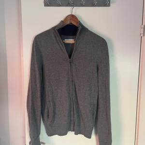 Grå zip tröja från pier one - En stilren grå kofta med hel dragkedja och ribbad krage. Tröjan har långa ärmar, fickor på sidorna och är tillverkad i ett mjukt material som passar perfekt för lager-på-lager. Enkel och clean look som funkar till många outfits. Tveka inte att höra av dig vid förnedringar!