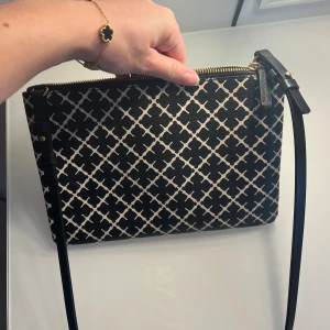 Malene Birger väska - Snygg axelväska i svart och vitt med ett rutigt mönster. Väskan har justerbar axelrem och stängs med dragkedja i guld. Insidan är beige och rymlig nog för det viktigaste. Knappt använd, inga defekter och i ny skick!!