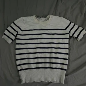 Randig kortärmad tröja från Zara - Vit och marinblå randig tröja från Zara i storlek S. Tröjan har korta ärmar och rund halsringning, perfekt för en chill och stilren look. Materialet känns mjukt och passar bra till både jeans och kjol.