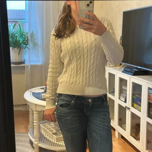 Vit kabelstickad tröja från Ralph Lauren - Kabelstickad vit tröja från Ralph Lauren med  rund halsringning och broderad rosa ralph lauren märke. Den är äldre modell så den är unik❤️.       St S/XS men säljer så den är lite liten på mig för min smak❤️