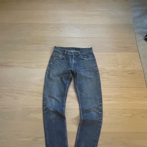 Tiger Of Sweden Feta Jeans - Snygga Tiger Of Sweden jeans. Perfekta för dig som gillar en stilren och enkel look. Inga slitningar. Storlek: W30 Mått:                                  •	Midja – 39 cm x 2 •	Grenhöjd – 25 cm •	Ytterbenslängd/Innerbenslängd – 103/77 cm •	Lårvidd – 28 cm x 2 •	Benslut – 16 cm x 2