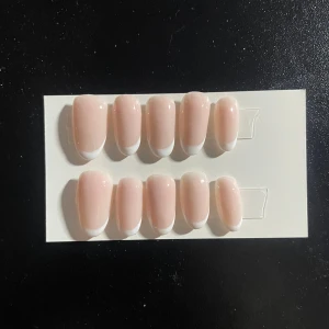 Franska lösnaglar i nude och vitt - Snygga lösnaglar med klassisk fransk manikyr-look. Naglarna är i en mjuk nude-rosa färg med vita tippar och har en glansig finish. Perfekt för dig som vill ha fräscha och stilrena naglar snabbt. Kommer på en praktisk bricka för enkel applicering.