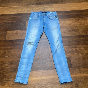 Ljusblå jeans från Replay - Säljer ett par replay Anbass i storlek 31/32. Längd 105 cm, bredd 38 cm. De har ett hål på högerknä och även smuts ovanför hålet.