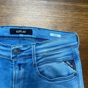 Replay Anbass ljusblå  jeans - Säljer ett par replay Anbass i storlek 31/32. Längd 105 cm, bredd 38 cm. De har ett hål på högerknä och även lite smuts ovanför hålet.