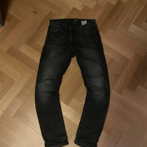 Svarta slim jeans Jack & Jones 29/30 - Svarta slim fit jeans från Jack & Jones, i modellen slim/glenn i storlek 29/30. Jeansen har klassisk femficksdesign, smal passform och är tillverkade i stretchigt denimtyg för extra komfort. Snyggt tvättade detaljer och modern look som passar till det mesta.
