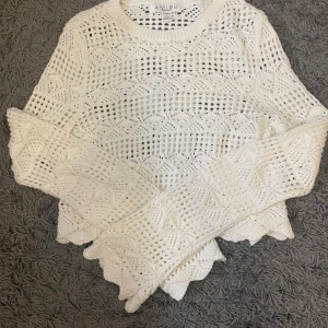 Vit stickad croppad tröja Amisu - Superfin vit stickad tröja från Amisu med croppad passform och långärmade ärmar. Tröjan har ett snyggt hålmönster och vågig kant nertill och vid ärmslut. Perfekt för vår och sommar när du vill ha en luftig och trendig look.