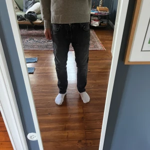Svarta jeansbyxor från Levis 511 - Säljer ett par svarta Nudie jeans med snygg tvättad look. Jeansen är i bomull och har en lätt stretch för extra komfort. Perfekta för dig som gillar en stilren och avslappnad vibe. Modell: Grim Tim 
