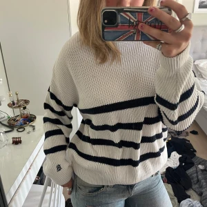 Bondelid Stickad Tröja - Säljer en vit stickad tröja från Bondelid med svarta horisontella ränder. Tröjan har en relaxed fit, ribbade muddar och rund halsringning. Perfekt för lager-på-lager och chill dagar. Klassisk och enkel att matcha med jeans eller kjol.