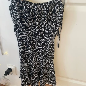 Svart klänning med blommor - Svart klänning med vita blommor, från new yorker & storlek xs, aldrig använd. Banden knyts.