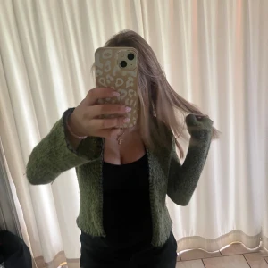 Grön stickad mohair kofta från Zoul - Säljer en mysig grön stickad mohair kofta från Zoul i storlek 34/36. Koftan har lång ärm, öppen framtill och coola mörka sömmar längs kanterna. Perfekt att slänga över en topp för en chill look.