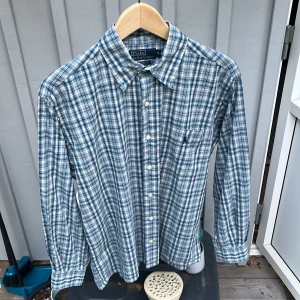 Rutig Ralph lauren skjorta  - Säljer en riktigt stilig raffe skjorta i super fint skick, skjortan är costom fit och 100% bomull med en bröstficka. kan släppa den lite billigare vid snabb affär skriv om ni har frågor så svarar jag så fort jag kan 