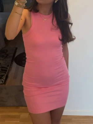 Rosa klänning  - Säljer en söt rosa kortklänning med ribbad struktur och ärmlös design. Klänningen har en rund halsringning och sitter tight mot kroppen, vilket ger en snygg och snatched look. Perfekt för varma dagar och enkel att styla med accessoarer.