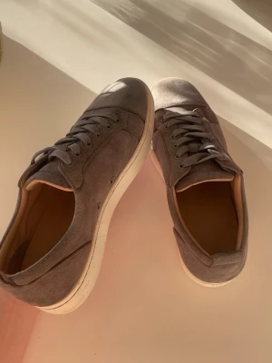 Grå mocka sneakers från Louboutin - Säljer ett par snygga gråa Christian loubution 🙌Dom är väldigt sköna skor som är perfekta inför sommaren och våren ☀️ dom har såklart den ikoniska röda sulan men har tyvärr lite smuts, om ni har några mer frågor så fråga mig gärna och priset är ej hugget i sten så kan gå ner i snabb affär 🤝 (OBS, kartong och annat ingår tyvärr inte, även så har skorna syn på användning och defekter )