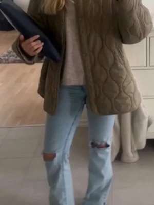 Grön jacka med knappar från H&M strl S - Säljer en quiltad grön jacka med snyggt vågigt mönster och knappar framtill. Jackan har en loose passform och är perfekt för lager-på-lager. Materialet känns som polyester och jackan är långärmad. Passar dig som gillar chill och stilren look. Strl S