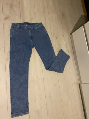 Blå jeans Tommy Hilfiger straight leg - Snygga blå jeans från Tommy Hilfiger med klassisk femficksdesign och broderad logga på bakfickan. Jeansen har raka ben, normal passform och är tillverkade i mjukt denim med tydliga sömmar och läderpatch i midjan.Tommy Hilfiger *   Jeans *   Denim *   Blå *   Vintage *   Andrahand *   Märkesskick *   Retro *   Straight leg   *   \#TommyHilfiger *   \#Jeans *   \#Denim *   \#VintageJeans *   \#SecondHand *   \#Vinted *   \#Märkeskläder *   \#RetroStyle *   \#HållbartMode
