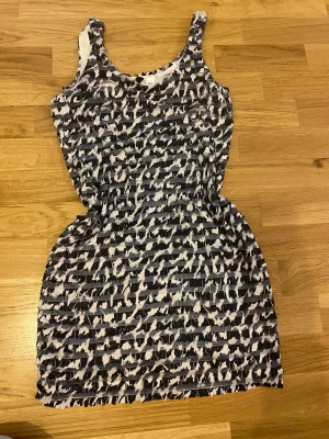 Svartvit mönstrad klänning H&M Divided - Säljer en cool svartvit kortklänning från H&M Divided i strl 38 alltså strl M. Klänningen har ett unikt mönster nästan  som zebra och är ärmlös med rund hals. Perfekt nu till nyår!! 