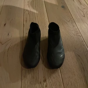 Svarta vattentäta skoöverdrag - Säljer ett par svarta adidas predator i syntetmaterial. De har en strömlinjeformad design och elastisk öppning för enkel påtagning. Passar storlek EU 42 (US 8.5, UK 8).