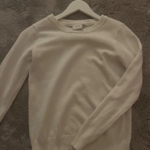 Vit stickad tröja från VILA - Säljer en enkel och stilren vit stickad tröja från VILA i storlek XS. Säljer pga ingen användning längre. Tröjan har två små fläckar längre ner och jag har försökt att få bort dem så bra jag kan men de syns endast i starkt ljus och om man kollar noggrant🩷